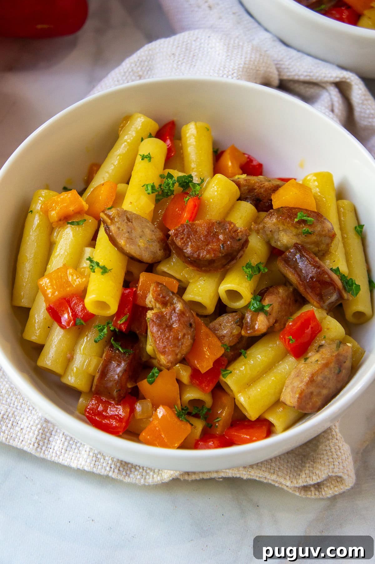 Sausage and Pepper Pasta Recipe — Quick Weeknight Dinner 2 a white bowl of ziti pasta tossed with cooked bell pepper and link sausage.