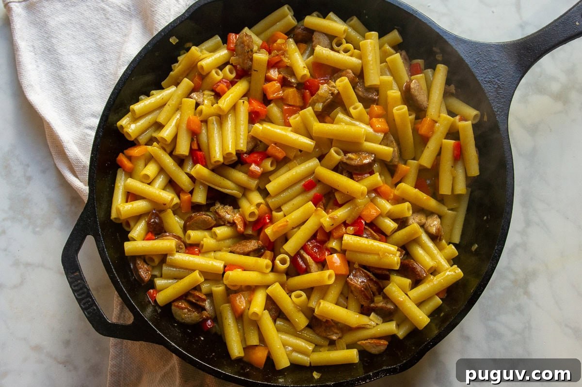 Sausage and Pepper Pasta Recipe — Quick Weeknight Dinner 6 A cast iron pan of pasta, sausage, and bell peppers cooked together.