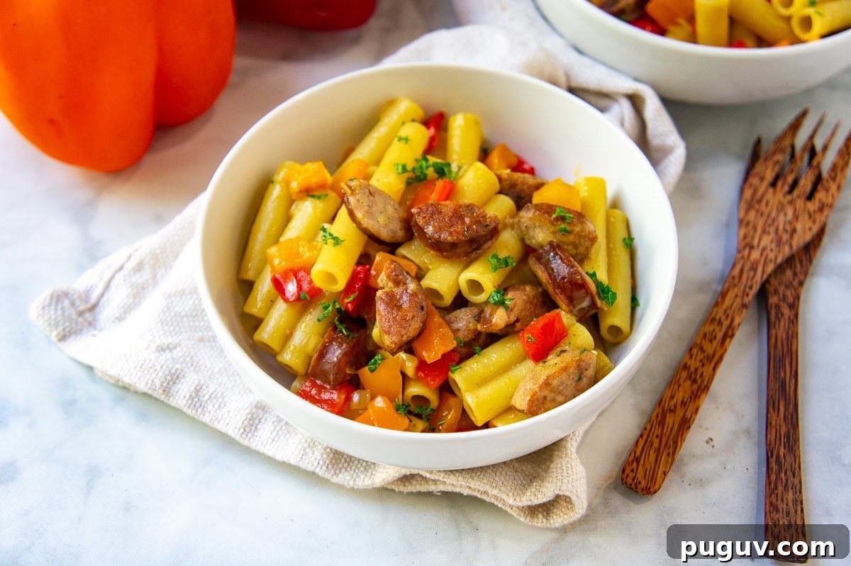 Sausage and Pepper Pasta Recipe — Quick Weeknight Dinner 7 a white bowl of pasta with sausage and peppers.