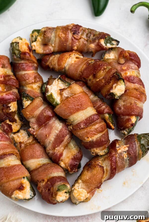 Crispy-On-The-Outside, Soft-On-The-Inside Air Fryer Pretzels 11 Crispy cooked bacon wrapped air fryer jalapeno poppers, filled with cheese mixture, on a white plate.
