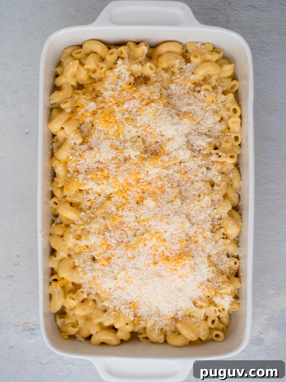 Creamy Baked Macaroni and Cheese Casserole 11 Mac and cheese in a baking dish with shredded cheese sprinkled on top.