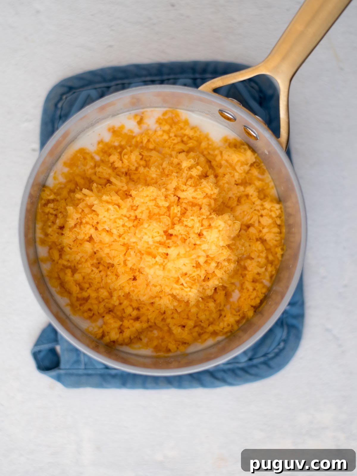 Creamy Baked Macaroni and Cheese Casserole 5 Shredded cheese added to a saucepan.