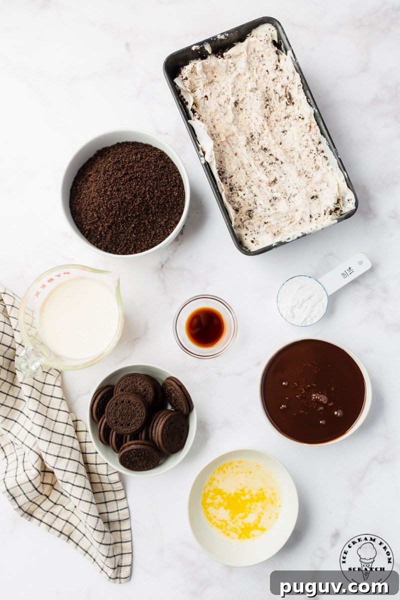 Decadent Oreo Ice Cream Cake Recipe for Parties and Birthdays 3 The ingredients needed for making an oreo ice cream cake, including homemade oreo ice cream, chocolate sauce, and crushed oreos, all in separate bowls on a marble countertop.