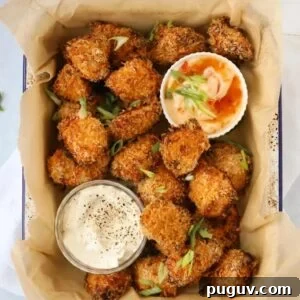 Crispy Homemade Chicken Nuggets Recipe for Family Meals 12 Coated golden homemade chicken nuggets in a baking dish with two pots of dips at the side.