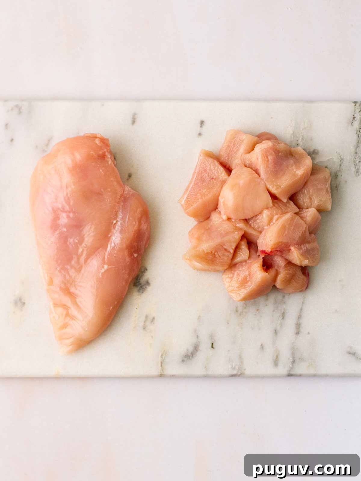 Crispy Homemade Chicken Nuggets Recipe for Family Meals 5 A chicken breast on the left hand side of a board, and cubes of chicken breast on the right hand side to show what it looks like chopped into pieces.