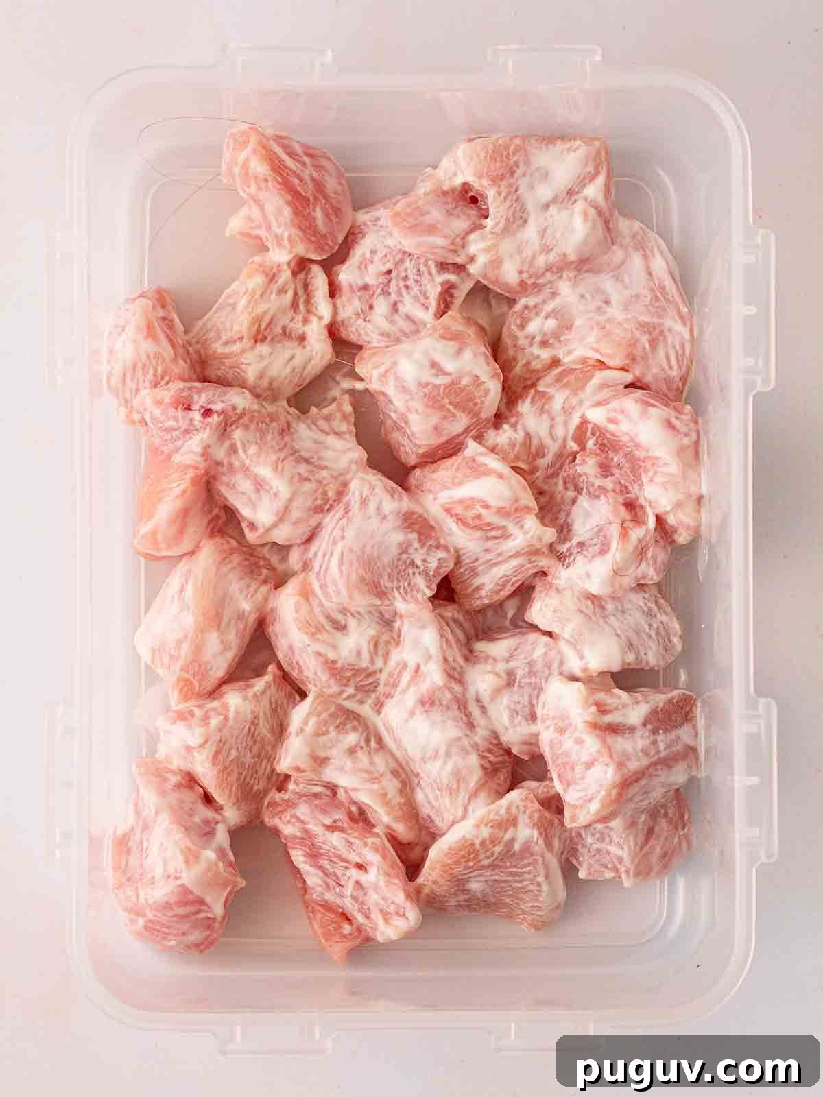 Crispy Homemade Chicken Nuggets Recipe for Family Meals 6 Pieces of raw chicken coated in Greek yoghurt in a Tupperware.