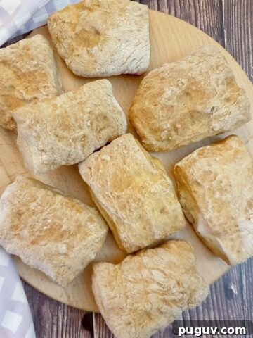 8 ciabatta rolls on wooden board.