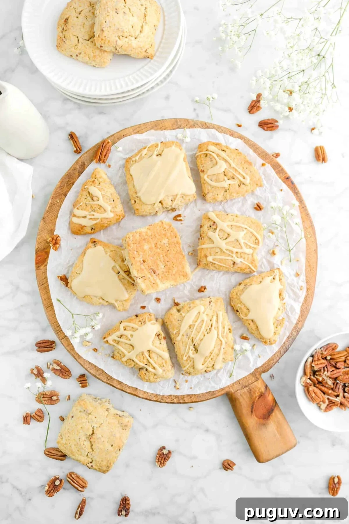 Maple Pecan Scones with Sweet Maple Glaze 2 nine glazed maple pecan scones on wood board with flowers, pecans, and more scones around