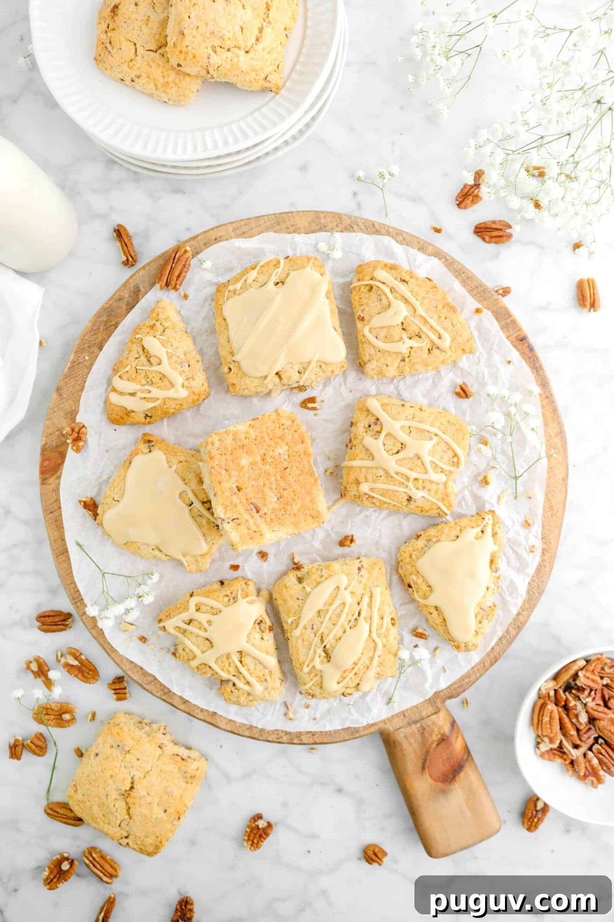 Maple Pecan Scones with Sweet Maple Glaze 8 nine glazed maple pecan scones on wood board with flowers, pecans, and more scones around