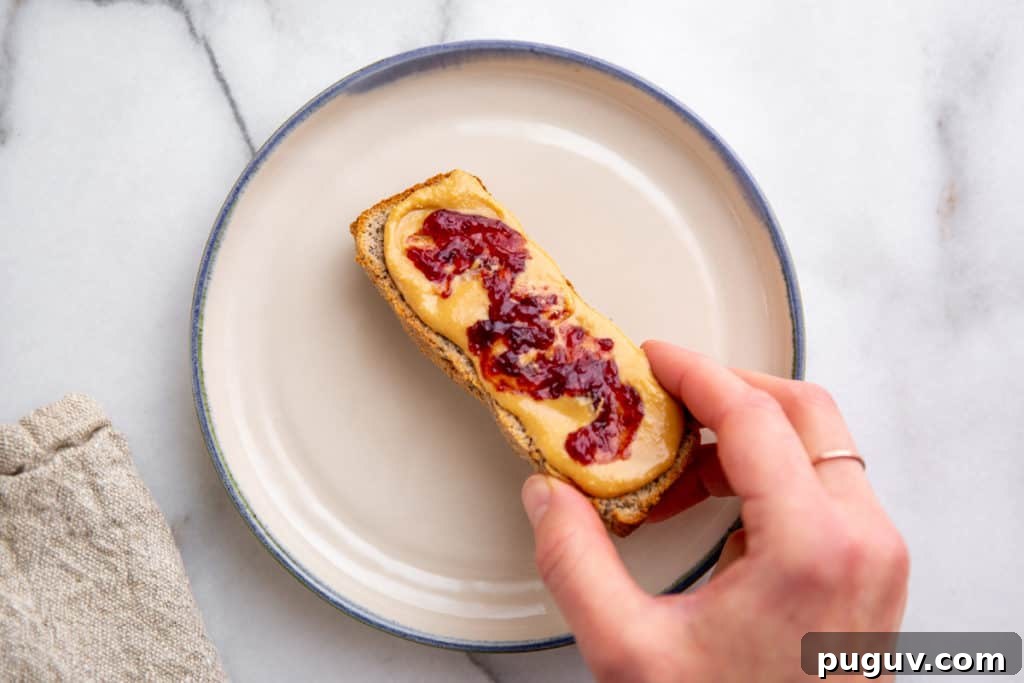 No-Yeast Vegan Almond Bread (Grain-Free, Paleo Recipe) 8 A hand picking up a piece of toasted almond flour bread topped with peanut butter and jelly.