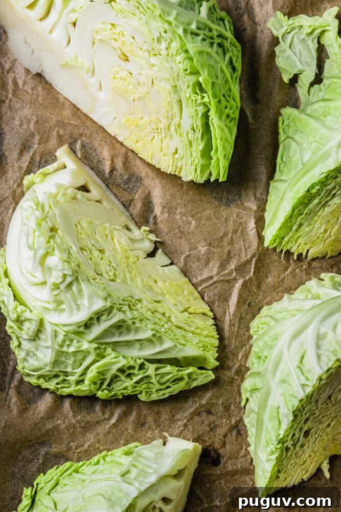 Crispy Roasted Cabbage with Olive Oil and Sea Salt 3 Raw savoy cabbage wedges on parchment paper ready to be roasted