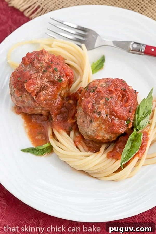 Mozzarella Stuffed Meatballs - Tender meatballs filled with gooey mozzarella Mozzarella Stuffed Meatballs with pasta on a white plate.