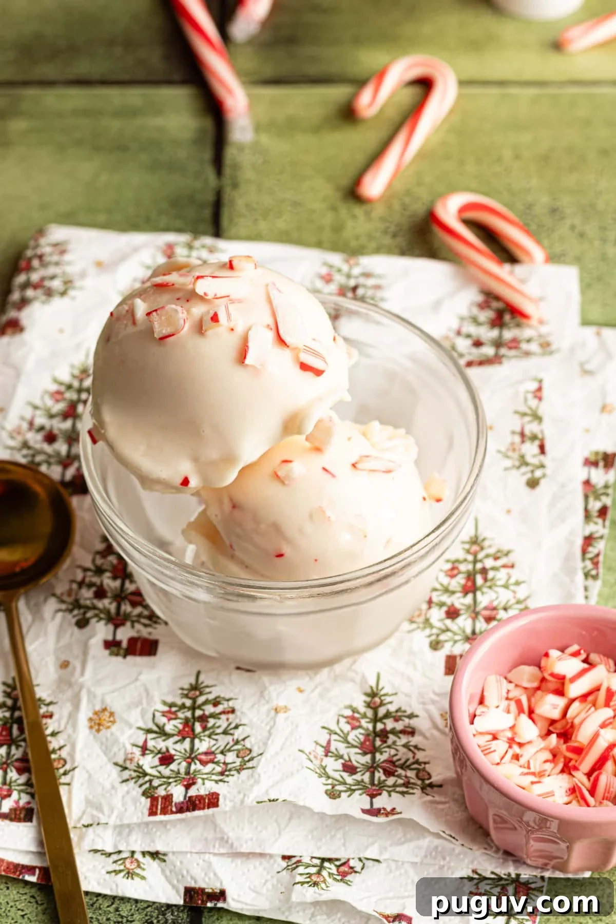 Two scoops of Ninja Creami peppermint ice cream in a clear dish on a christmas tree napkin.