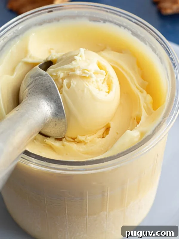 A Ninja Creami pint container full of protein ice cream with an ice cream scoop.