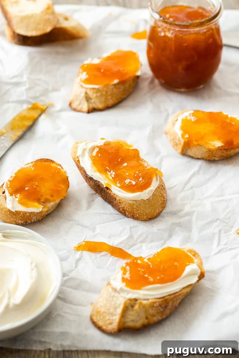 Pieces of bread topped with cream and jam, sitting on some baking paper.