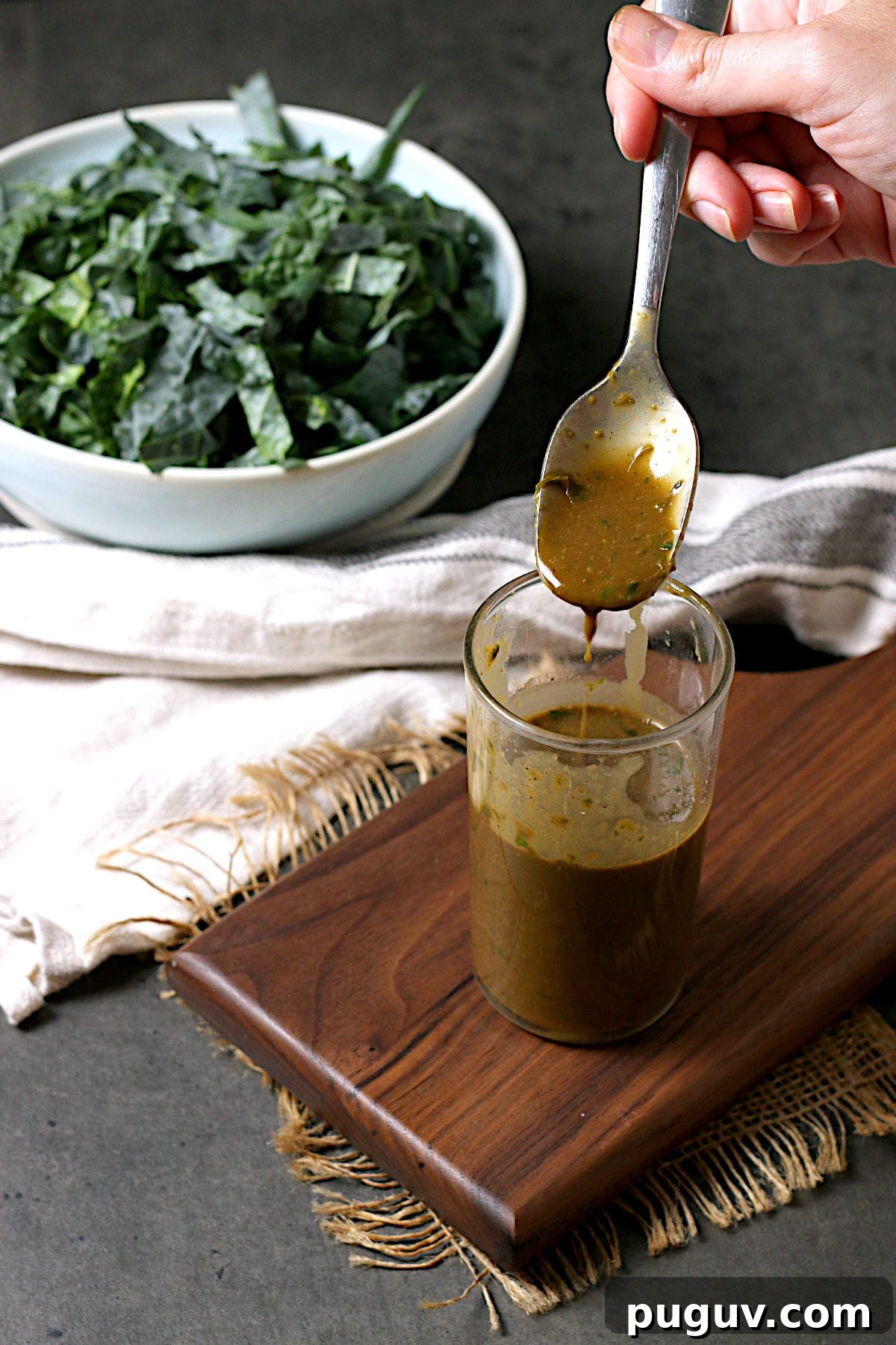 Basil Balsamic Vinaigrette Recipe — Tangy Herb Dressing for Salads 4 A hand holding a spoonful of Basil Balsamic Vinaigrette.