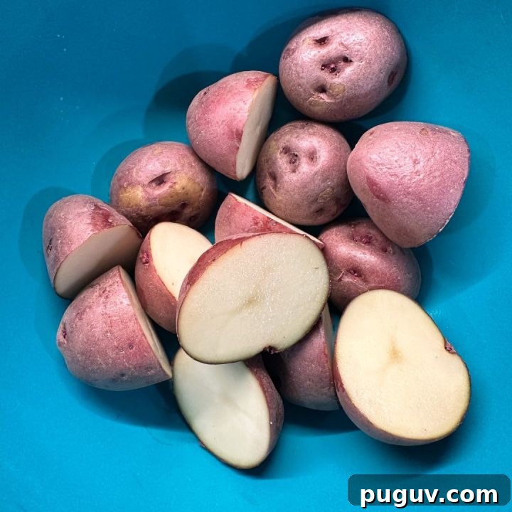 Wash and dry the potatoes thoroughly. Cut them in half to create a flat surface for maximum contact with the Parmesan crust.