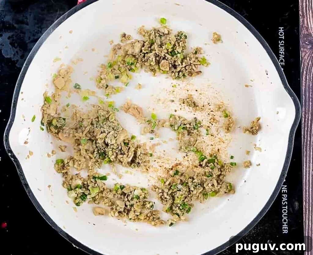 The cooked onion and mushroom mixture in a white skillet.