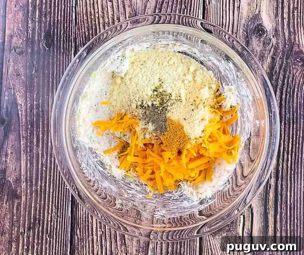 The cheese and seasoning added to the cooked mushroom and onion mixture in a glass bowl.