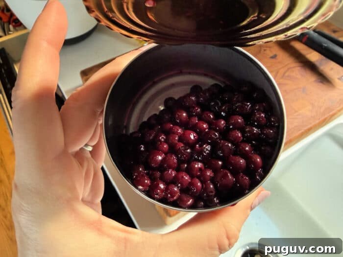 Upgrade Your Blueberry Muffin Mix: Simple Tips for Moist, Flavorful Muffins 5 A hand holds an open can filled with dark purple berries over a kitchen sink and cutting board—perfect for learning how to make blueberry muffin mix better.