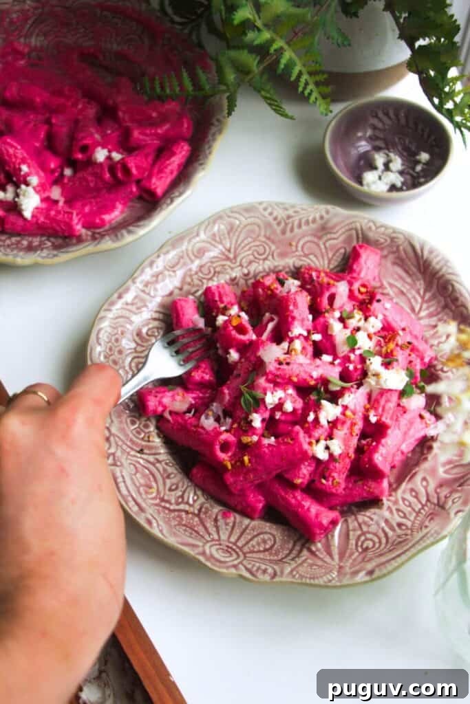 Spicy ’Nduja Pasta with Creamy Burrata Cheese 12 Hand holding a fork digging into plate of bright pink pasta.
