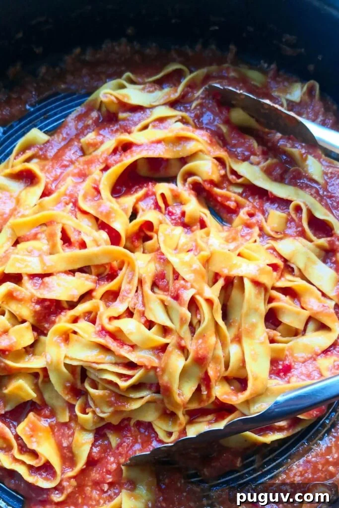 Spicy ’Nduja Pasta with Creamy Burrata Cheese 8 Nduja pasta being tossed through sauce with large silver tongs in a pan.