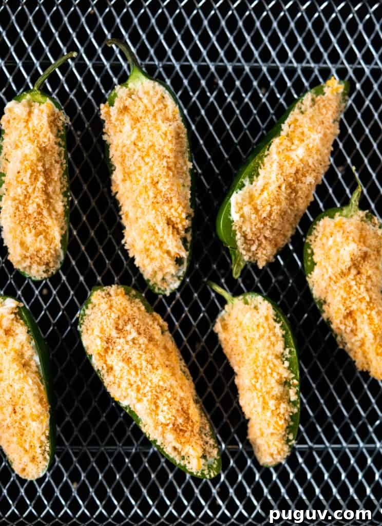 Crispy Air Fryer Jalapeño Poppers: Cream Cheese Stuffed Bites 6 uncooked filled and breaded jalapeño poppers on an air fryer basket