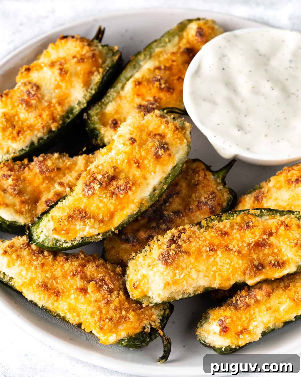 Crispy Air Fryer Jalapeño Poppers: Cream Cheese Stuffed Bites 9 Plate full of jalapeño poppers with a small bowl of white dipping sauce