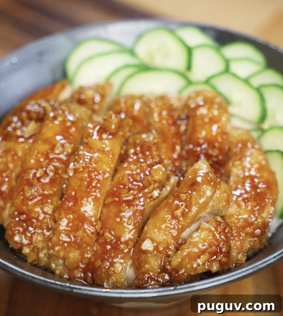 Crispy Honey Garlic Chicken Recipe — Sticky Glazed Chicken Drumsticks 2 Sliced honey garlic chicken thighs served over a bowl of white rice with fresh cucumber slices on the side, showcasing the glossy, sticky glaze.