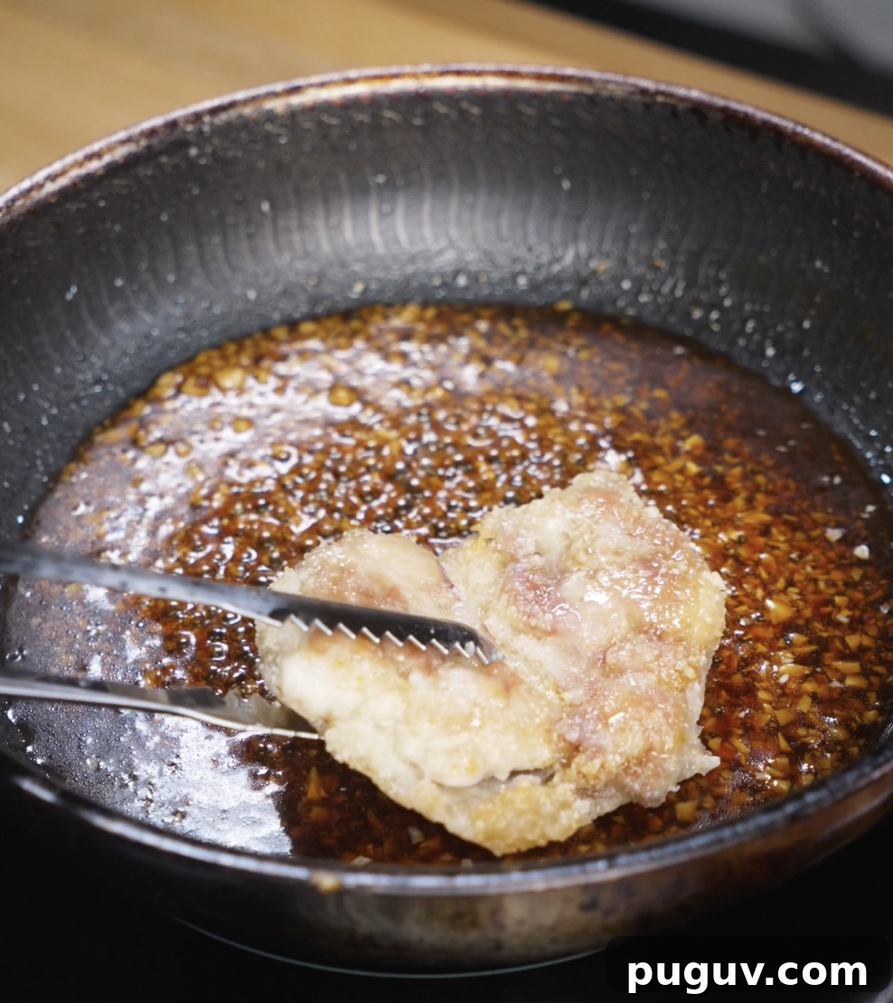 Crispy Honey Garlic Chicken Recipe — Sticky Glazed Chicken Drumsticks 7 Fried chicken thighs are returned to the pan and tossed in the thickened honey garlic sauce until fully coated and glossy.