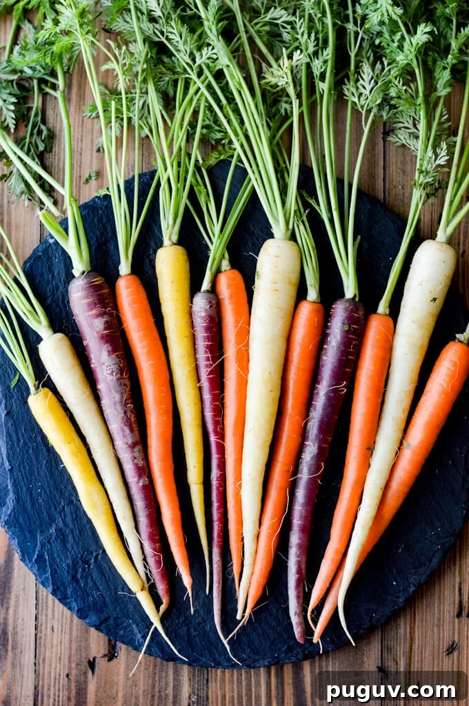 A bunch of rainbow carrots with green stems on a black round tray.