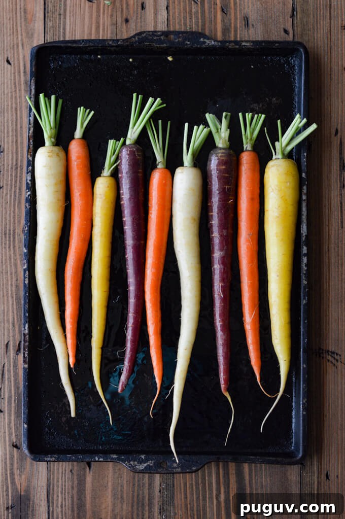 A pan of raw rainbow carrots ready to go in the oven.