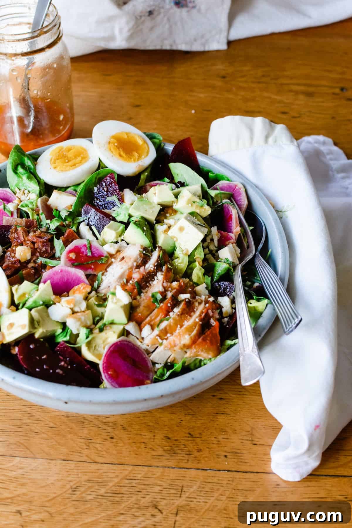 Autumn Harvest Cobb Salad with Cranberries, Apples & Goat Cheese 3 A Cobb Salad recipe made with chicken, feta, avocado, and lettuce in a big bowl on a wooden table.