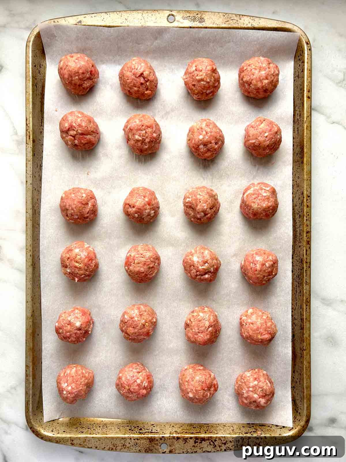 Classic Italian Wedding Soup Recipe — Authentic Homemade Flavor 4 raw meatballs arranged on parchment-lined baking sheet.