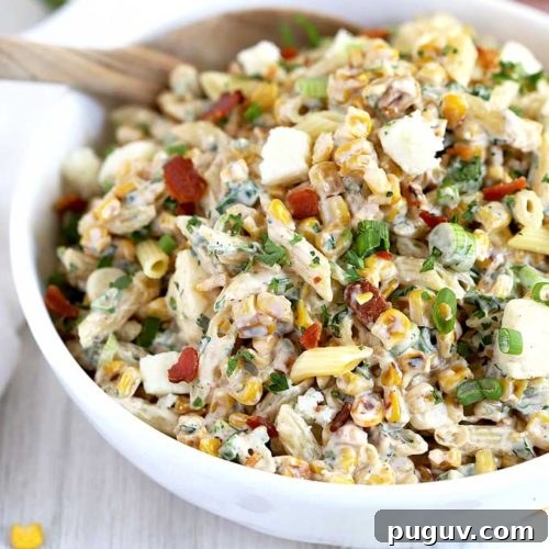 Mexican Street Corn Pasta Salad in a white bowl with a serving spoon.
