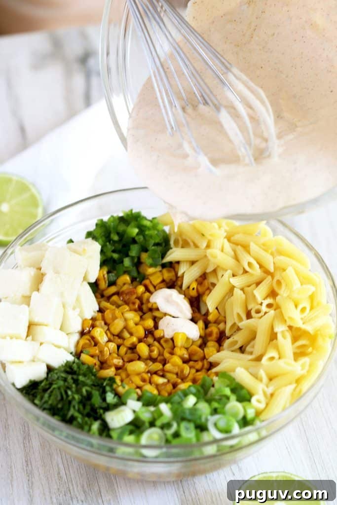 Mexican Street Corn Pasta Salad Recipe with Chili-Lime Dressing 8 pouring the chili lime dressing over the salad