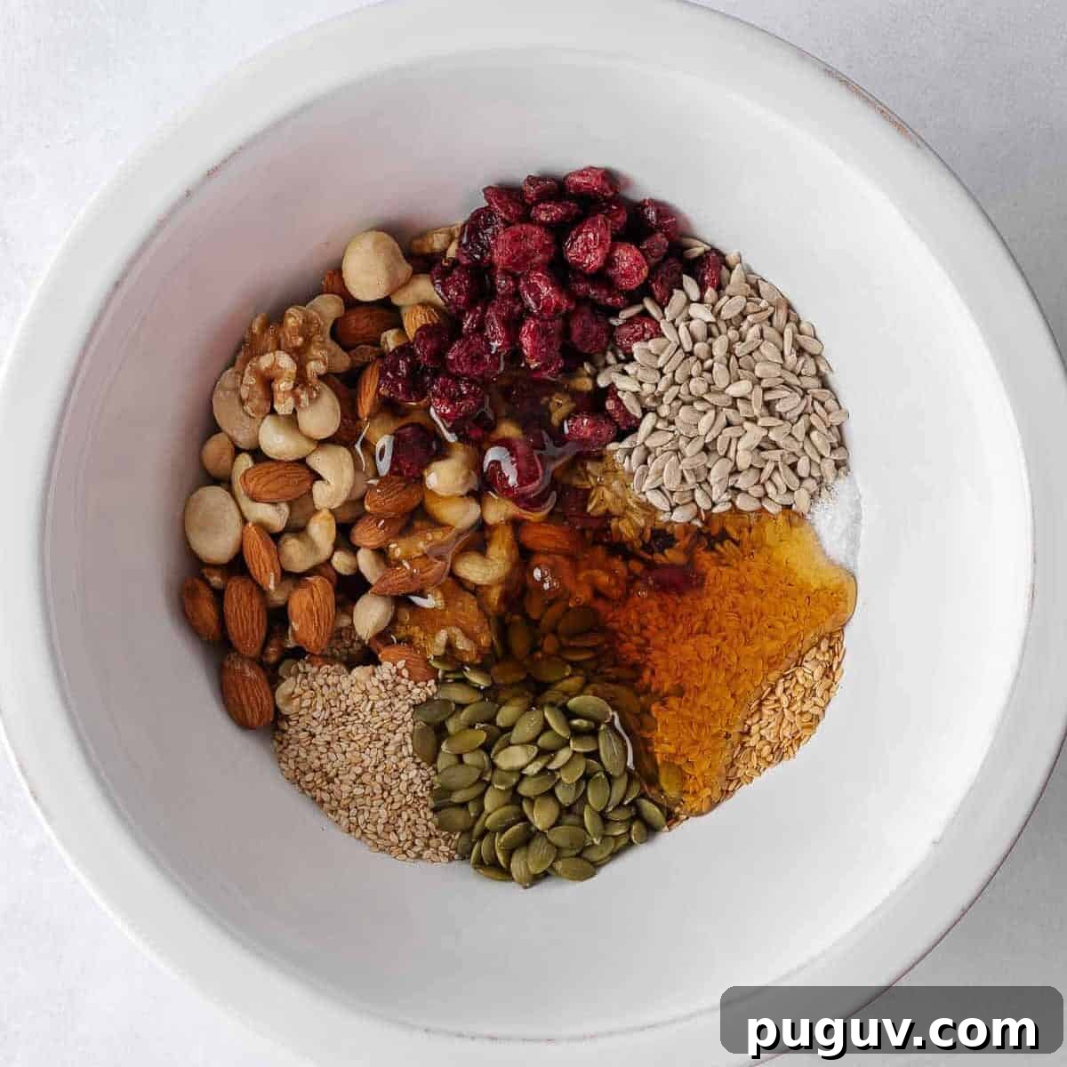 Homemade Fruit and Nut Bars Recipe for Energy and Snacking 4 Nuts and seeds combined with honey mixture in a bowl.