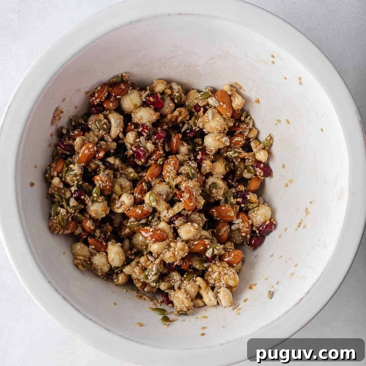 Homemade Fruit and Nut Bars Recipe for Energy and Snacking 5 Nuts and seeds combined with honey mixture in a bowl.