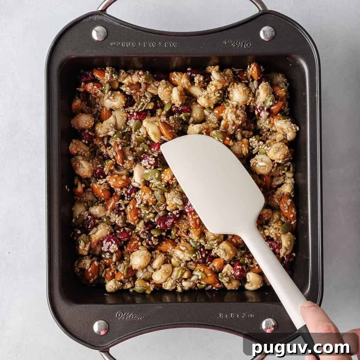 Homemade Fruit and Nut Bars Recipe for Energy and Snacking 7 A spatula presses the healthy nut bar recipe into a pan.