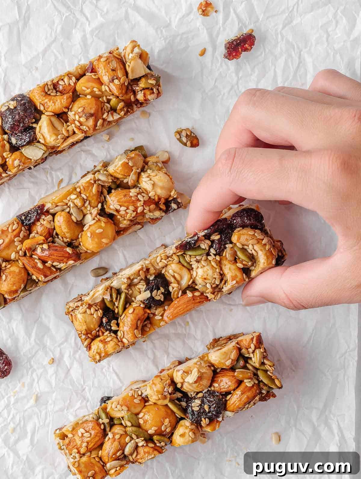 Homemade Fruit and Nut Bars Recipe for Energy and Snacking 9 A hand picks up a seed and nut bar.