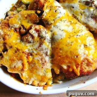 Cheesy Chicken and Roasted Veggies Sheet Pan Recipe 5 cooked chicken with melted cheese on top of veggies in white baking dish