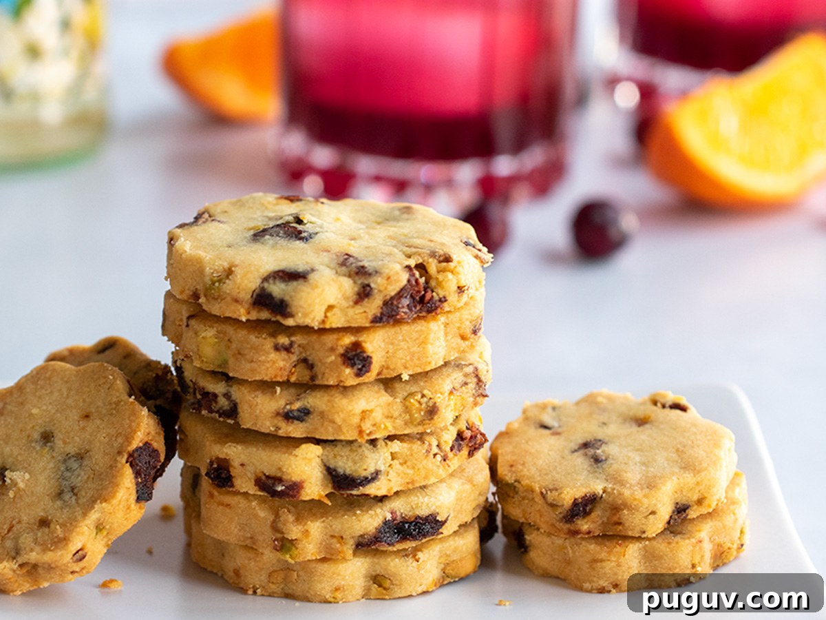 Close up of a stack of cookies on a white plate with a cocktail in the background.