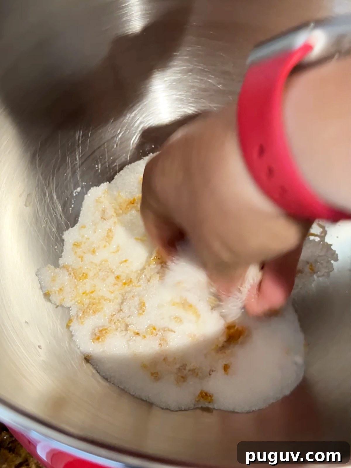 Mixing orange zest and sugar in stand mixer bowl for cranberry orange shortbread dough.