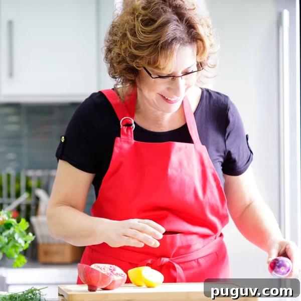 Beth Lee in red apron looking at vegetables on cutting board