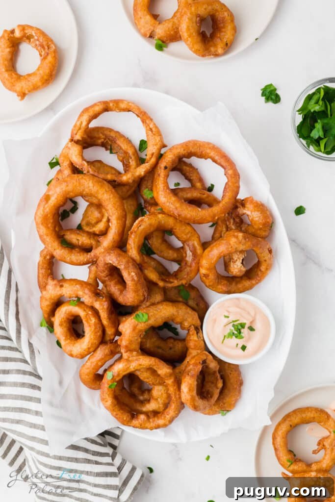 An oval platter of battered onion rings with a side of creamy dip.
