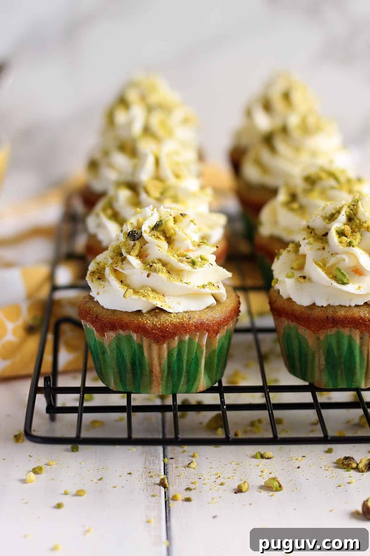 Pistachio cupcakes on a wire rack.