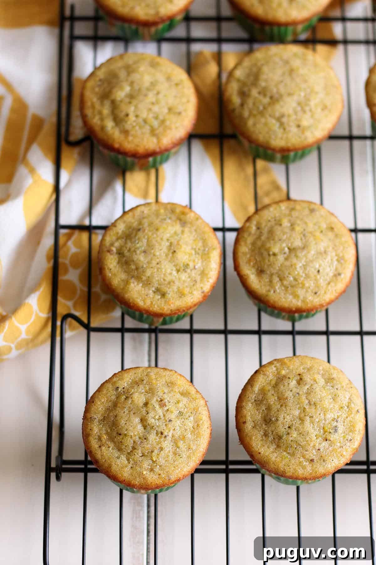 Pistachio Cupcakes are cooling on a black wire rack.