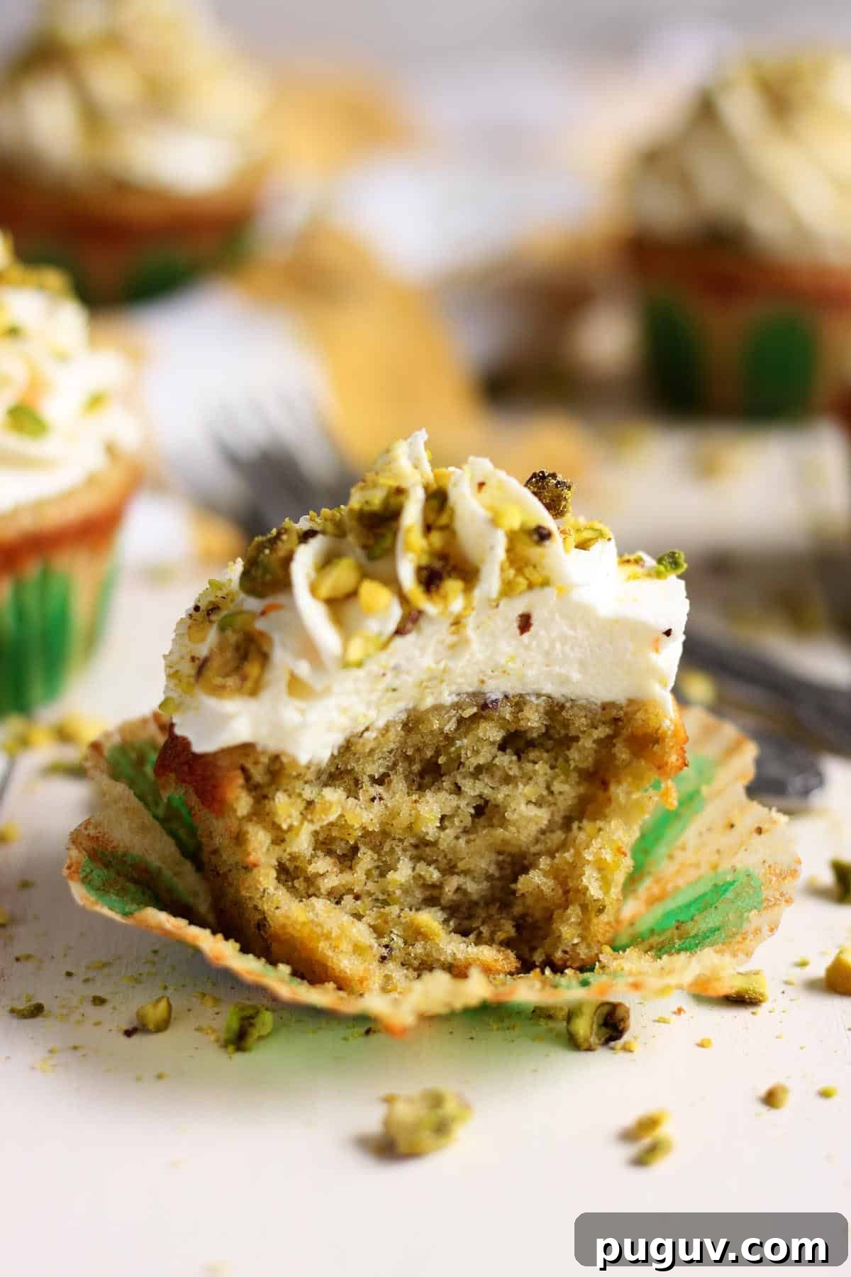 A pistachio cupcakes with a bite taken out of it.