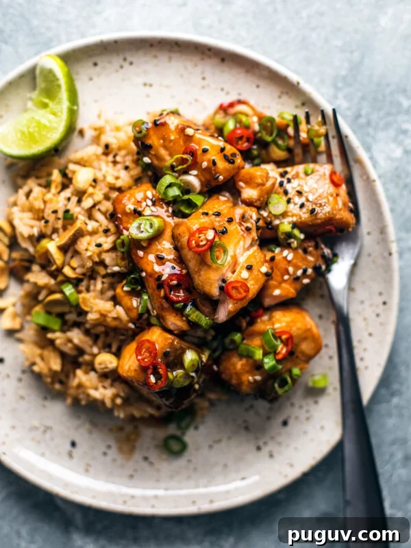 Crispy Air Fryer French Fries with 3 Ingredients 14 Plate with rice topped with cubed salmon tossed in sweet chili sauce and garnished with scallions and chilies.