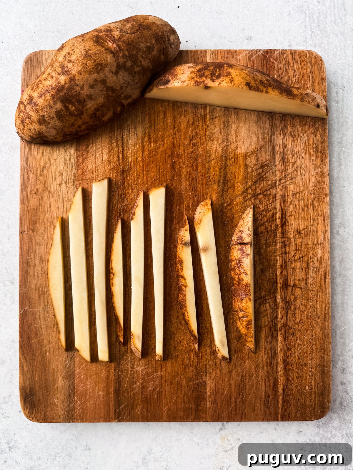 Crispy Air Fryer French Fries with 3 Ingredients 6 Uncooked fries cut up in uniform shapes on a cutting board.